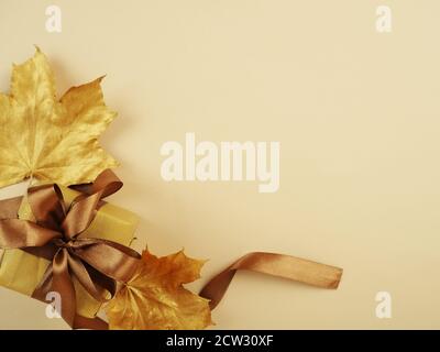 Herbst Stillleben mit Gruppen-Geschenkbox. Goldene Ahornblätter und Geschenk mit Band, Platz für Design und Text Stockfoto