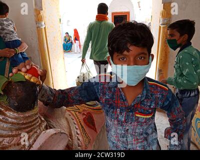 DISTRIKT KATNI, INDIEN - 08. JULI 2020: Traditioneller indischer Junge, der Facemask für Coronavirus-Schutz am hinduistischen religiösen Ort trägt, während der Reise. Stockfoto