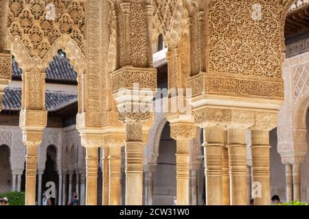 Maskierte Touristen besuchen den Patio de los Leones der Alhambra in Granada. Stockfoto