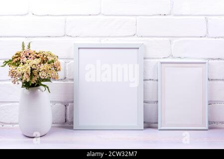 Zwei weiße Rahmen Mockup mit rosa Schafgarbe Wildblumen in der Vase. Leerer Posterrahmen für Präsentationsgestaltung. Schablonenrahmen für moderne Kunst Stockfoto