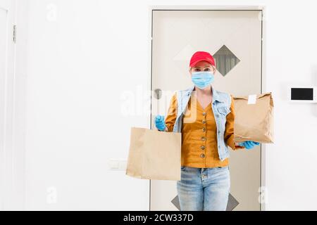 Maskierte Geburt Frau liefert Nahrung während Virusausbruch, Coronavirus Panik und Pandemien. Stockfoto