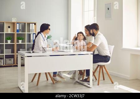 Freundliche Kinderärztin spricht mit einer jungen Familie, die ihre Tochter zur Untersuchung brachte. Stockfoto