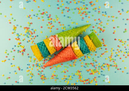 Set aus verschiedenen hellen bunten Eis Waffelkonen auf blau Hintergrund mit verstreuten Konfetti Zucker bestreut Stockfoto