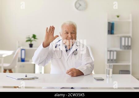 Freundlicher Arzt winkt Hand begrüßen Kunden im Krankenhaus Büro oder Auf seinem medizinischen Videokanal Stockfoto