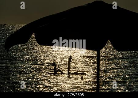 Paar Stand-up Paddling auf einem Meer während des Sonnenuntergangs auf einem Sommer Stockfoto