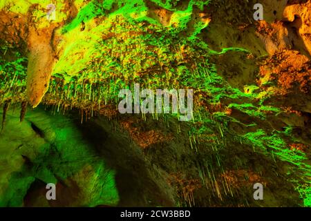 Magisches Innere der alten Kalksteinhöhle, fantastische grüne Stalagmite glüht in Lichtern. Khao Bin Cave, Ratchaburi, Thailand. Low-Angle-Ansicht. Stockfoto