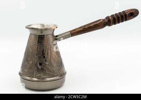 Kupfer-Türke oder Cezve mit einem Holzgriff zum Brühen von Kaffee isoliert auf einem weißen Hintergrund. Stockfoto
