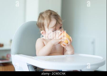 Baby essen einen Apfel auf einem Hochstuhl sitzen Stockfoto