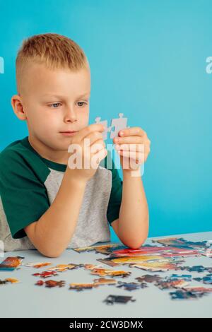 Porträt eines Jungen verbindet Puzzles.auf einem blauen Hintergrund Stockfoto