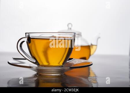 Nahaufnahme einer Tasse frisch gebrühten heißen Tees in transparentem Glas und Teekanne auf dem Tisch. Stockfoto