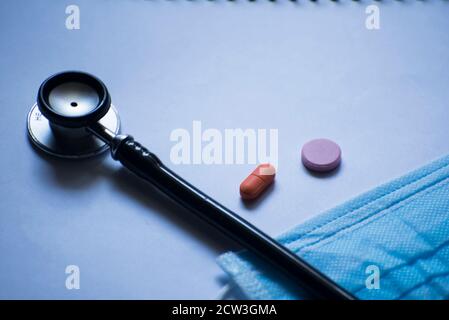 Stethoskop, Gesichtsmaske und Medizin isoliert auf blauem Hintergrund Stockfoto