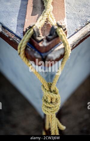 Eine Nahaufnahme von Bootsseilen, die um den herum gebunden sind Klammer auf dem Bug eines Holzbootes mit selektiven Fokus Stockfoto
