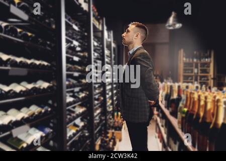 Der Barkeeper Sommelier holt eine Flasche Wein aus dem Regal im Restaurant und serviert exquisite Getränke Stockfoto