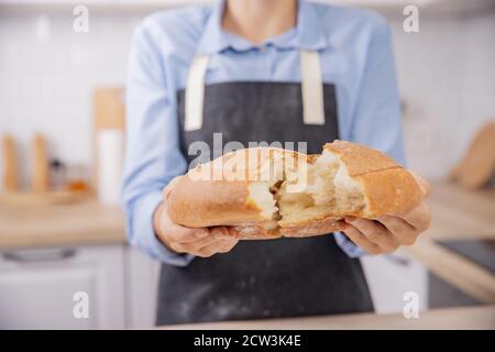 Baker Hände brechen heiße frische runde Weizenbrot in zwei Hälften, Crunch und Krümel Stockfoto