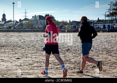 Portobello, Edinburgh, Schottland, Großbritannien. 27. September 2020. Nach dem jüngsten Regierungsratschlag, der die Öffentlichkeit auffordert, aktiv zu bleiben, um psychische Gesundheit und andere gesundheitliche Probleme zu vermeiden, scheinen die Menschen, die heute an der sonnigen Küste abgebildet sind, zu beachten, Abgesehen von einer Gruppe junger Menschen, die sich nicht bewusst zu sein scheinen, dass es notwendig ist, sich in kleinen Gruppen sozial zu distanzieren, während sie in einer Gruppe von fast einem Dutzend auf dem Sand sitzen. Herbstliches Wetter mit einer Temperatur von 4 Grad nach einer kalten Nacht und Morgen hat die Leute nicht in halten, da sie die geschäftige Atmosphäre genießen. Stockfoto