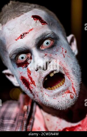 Zombie aus in der Nacht Wunden Schnitte und Blut befleckt zerrissene Kleidung, schlechte Zähne stechenden Augen bedrohende Haltung und Ausdruck im Hochformat. Stockfoto