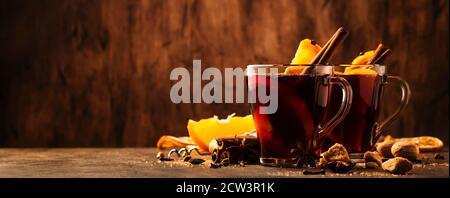 Heißer Glühweinbecher mit Gewürzen und Früchten auf rustikalem Holztisch. Traditionelles Heißgetränk im Herbst, Kopierbereich Stockfoto
