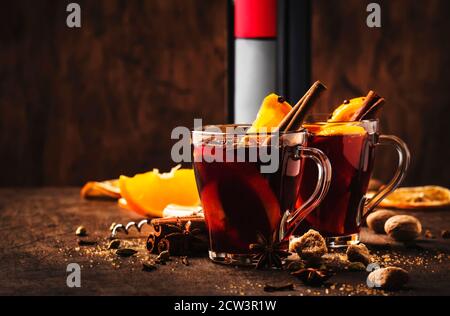 Heißer Glühweinbecher mit Gewürzen und Früchten auf rustikalem Holztisch. Traditionelles Heißgetränk im Herbst, Kopierbereich Stockfoto