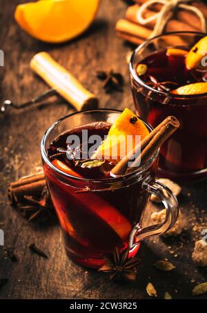 Heißer Glühweinbecher mit Gewürzen und Früchten auf rustikalem Holztisch. Traditionelles Heißgetränk im Herbst, Kopierbereich Stockfoto
