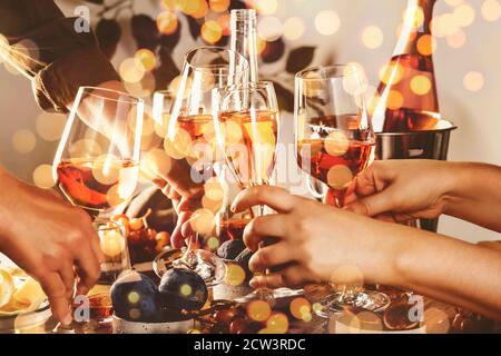 Hände halten Gläser mit Roséwein über dem Tisch serviert Für festliche Dinner-Party mit verschiedenen Arten von Vorspeisen und Früchte Stockfoto