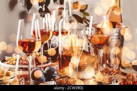 Roséwein Gläser und Flaschen auf dem Tisch serviert für festliche Dinner Party mit verschiedenen Arten von Vorspeisen und Obst Stockfoto