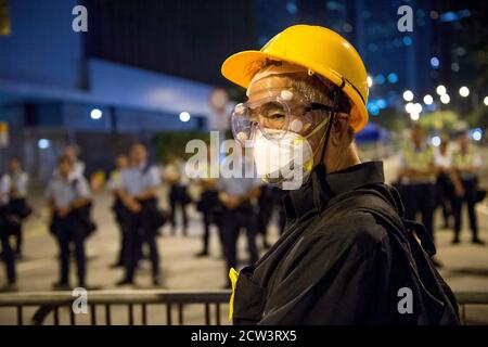 HONGKONG, HONGKONG SAR, CHINA: 5. OKTOBER 2019. Die Umbrella Revolution von 2014. Die Polizei verbarrikadiert die Straße durch die Regierungsstellen. Ein Protestler steht Stockfoto