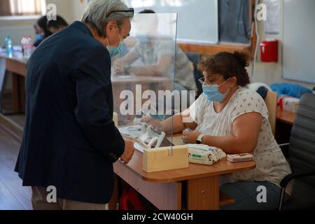 Bukarest. September 2020. Ein Mann mit Gesichtsmaske zeigt seinen Personalausweis, bevor er bei den Kommunalwahlen in Bukarest, Rumänien, am 27. September 2020 seine Stimme abgegeben hat. Quelle: Gabriel Petrescu/Xinhua/Alamy Live News Stockfoto