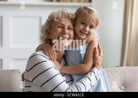 Glücklich gealterte Großmutter hält kleine VorschulEnkelin in den Armen Stockfoto