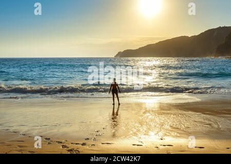 Silhouette eines Mannes, der am Strand steht und auf den Sonnenuntergang blickt, Kelingking Beach in Bali, Indonesien. Stockfoto