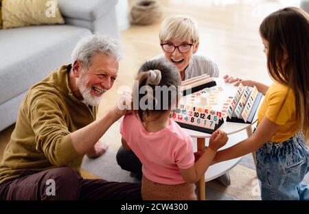 Enkelkinder, die zu Hause Spaß haben, während sie mit ihren Großeltern spielen Stockfoto