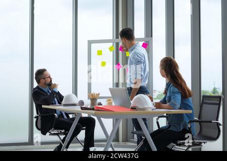 Team von multiethnischen Architekten arbeiten an Bauplänen im Besprechungsraum. Ingenieure diskutieren über Projekt im Büro. Stockfoto