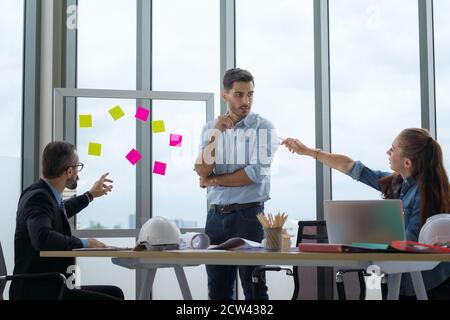 Team von multiethnischen Architekten arbeiten an Bauplänen im Besprechungsraum. Ingenieure diskutieren über Projekt im Büro. Stockfoto