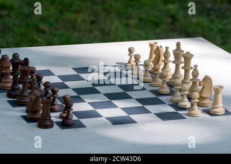 Holzschachfiguren stehen vor dem Outdoor-Turnier auf dem Schachbrett. Stockfoto