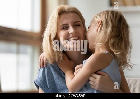 Nette kleine Tochter umarmt glücklich lächelnd Erwachsene Mutter Stockfoto