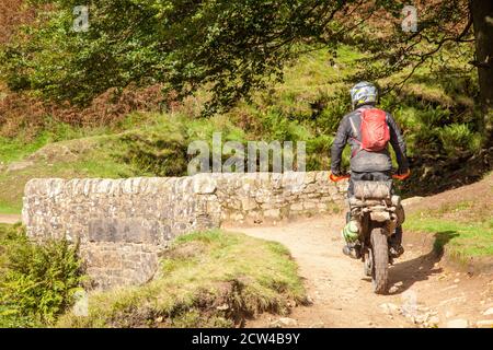 Off-Road-Motorradfahrer mit einer grünen Spur Weg überqueren die Steinbrücke an den drei Shires Kopf in der Spitze District National Park England Großbritannien Stockfoto