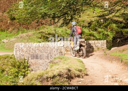 Off-Road-Motorradfahrer mit einer grünen Spur Weg überqueren die Steinbrücke an den drei Shires Kopf in der Spitze District National Park England Großbritannien Stockfoto