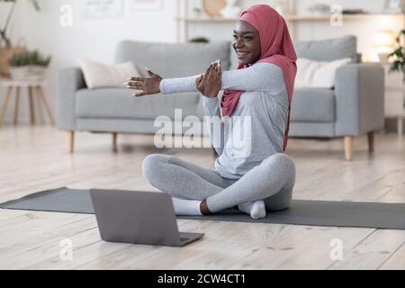 Quarantäneschulungen. Sportliche Afrikanische Muslimische Frau Ausübung Vor Dem Laptop Stockfoto