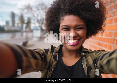 Porträt einer jungen schönen afro-amerikanischen Frau, die ein Selfie im Freien auf der Straße. Stockfoto