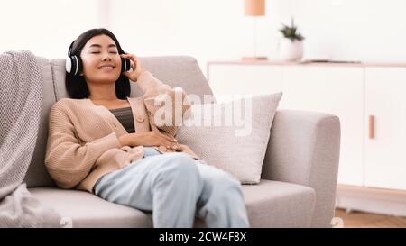 Asiatische Frau, die Musik mit kabellosen Kopfhörern hört Stockfoto