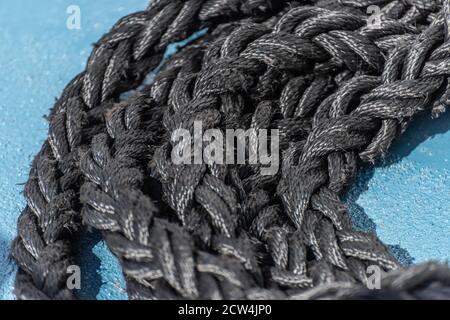 Dickes, schwarzes Seil auf blauem Schiffsdeck Stockfoto