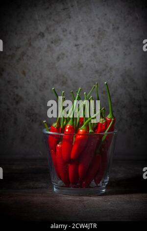 Stillleben Foto von Red Peppers in Glasvase auf Grunge Hintergrund Stockfoto