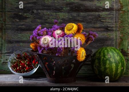 Stillleben Horto von roten Paprika, getrocknete Blumen in Eisen Vase Mit Wassermelone Stockfoto