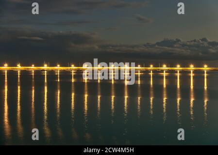 Wunderschöne Hafenlaternen Beleuchtung am Abend. Reflexion des Lichts im Wasser. East Pier von Dun Laoghaire Hafen während der blauen Stunde, Dublin Stockfoto