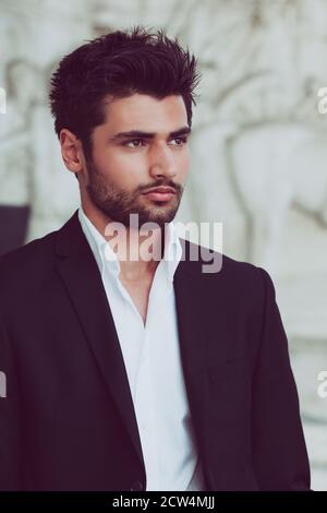 Schöner und junger Mann mit stylischem Haar und Bart. Porträt des charmanten Mannes. Weißes Hemd und Jacke. Stockfoto