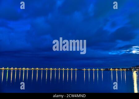 Wunderschöne Hafenlaternen Beleuchtung am Abend. Reflexion des Lichts im Wasser. East Pier von Dun Laoghaire Hafen während der blauen Stunde, Dublin Stockfoto