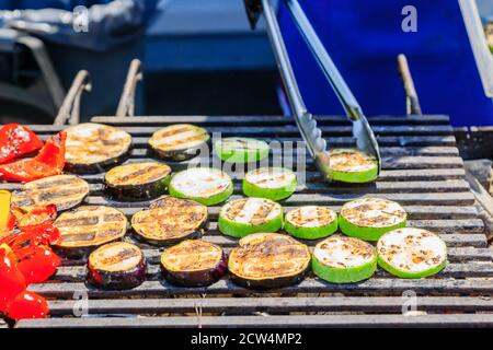 Der Koch kocht Gemüse auf dem Grill. Zuccini-Scheiben, Auberginen, Pfeffer auf offenem Feuer geröstet Stockfoto