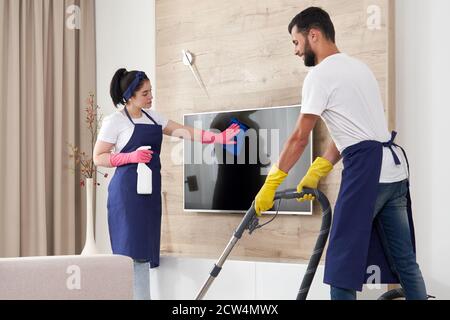 Professionelles Reinigungsservice-Team reinigt Wohnzimmer in modernen Wohnung Stockfoto