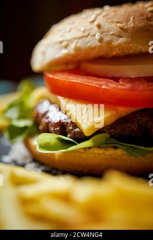 Cheeseburger umgeben von pommes auf einem schwarzen Tisch Stockfoto