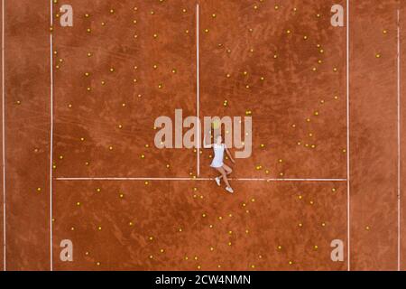 Portrait von lächelndem Mädchen entspannen auf dem Tennisplatz mit einer Menge Bälle und Schläger nach harten Tennis trainingg im Freien. Dolly-Schuss. Draufsicht. Stockfoto