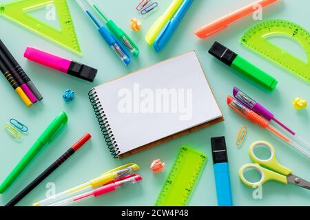 Schul- und Büroartikel, farbige Stifte, Heftklammern, Filzstifte, Set Quadrate, ein leeres Notizbuch für den eigenen Text in der Mitte. Stockfoto